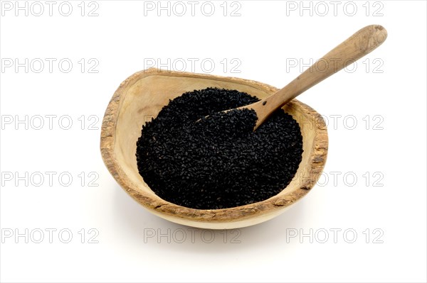 Nigella seeds in a wooden rustic bowl with a wooden spoon against a white background