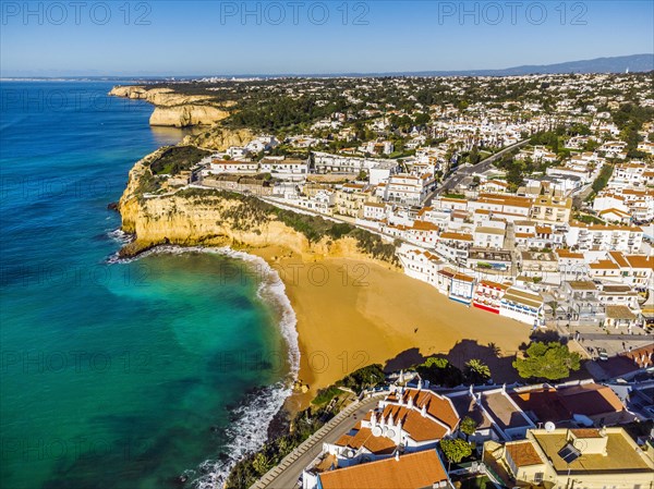 Aerial view of wide sandy beach and traditional architecture of Carvoeiro in Algarve