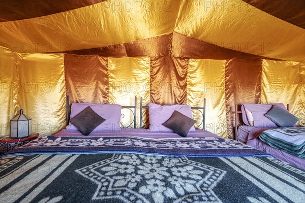 Three beds inside elegant tent set on Sahara desert
