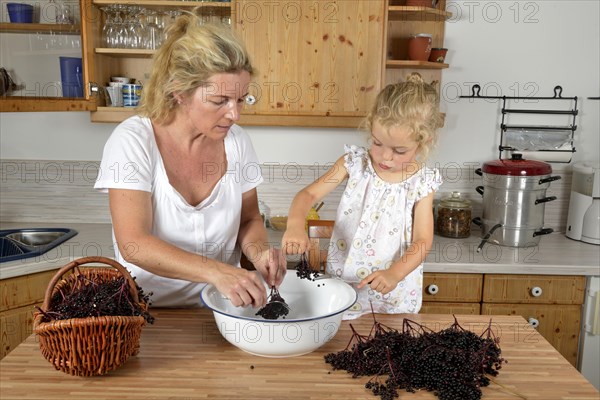 Woman and girl cooking elderberry juice