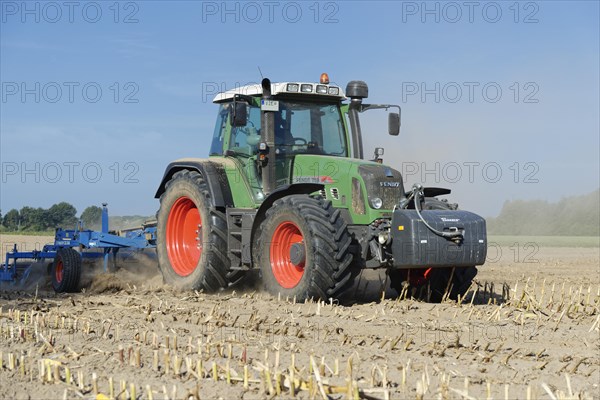 Farmer cultivating harvested maize field