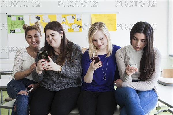 Vocational school students with their smartphones during break at the Elly-Heuss-Knapp-Schule