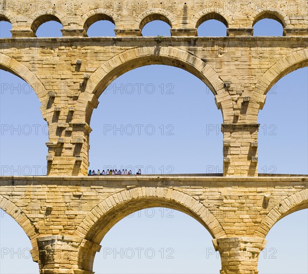 A group of tourists resting in the shadow of the Pont du Gard