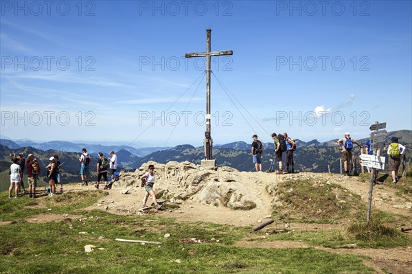 Hiker at the summit cross at Riedberger Horn