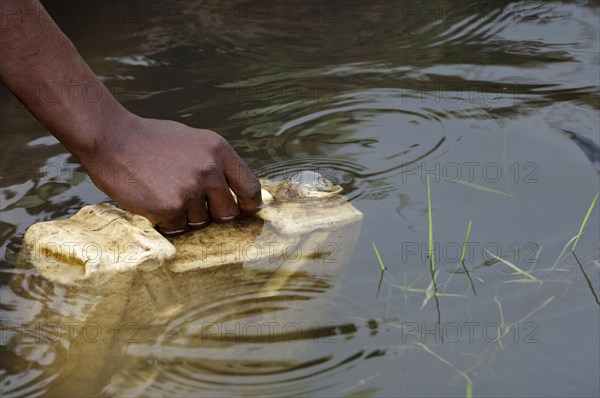 Collecting container of water from dirty pool of water