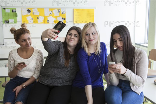 Vocational school students with their smartphones during break at the Elly-Heuss-Knapp-Schule