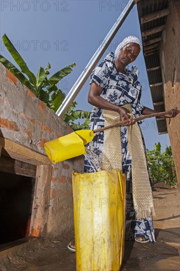 Woman getting water from storage pit