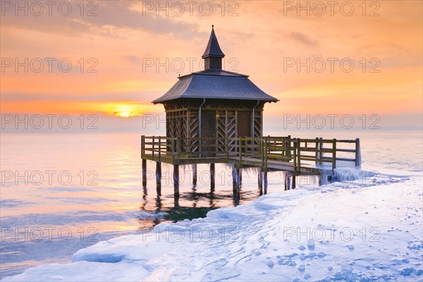 Iced wooden bathhouse at sunrise on Lake Neuchatel in Gorgier