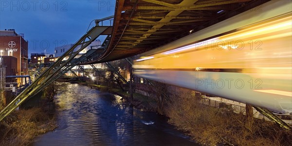 Light track of a moving suspension railway over the river Wupper at the Bayer plant