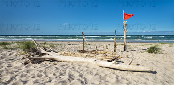 Untouched beach with driftwood and red flag