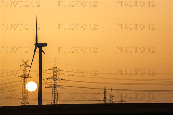 Wind turbine and power pole at sunset
