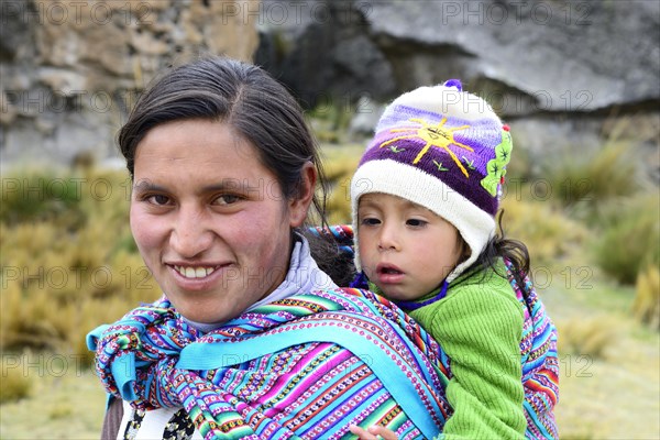 Smiling indigenous woman with falling asleep infant on her back