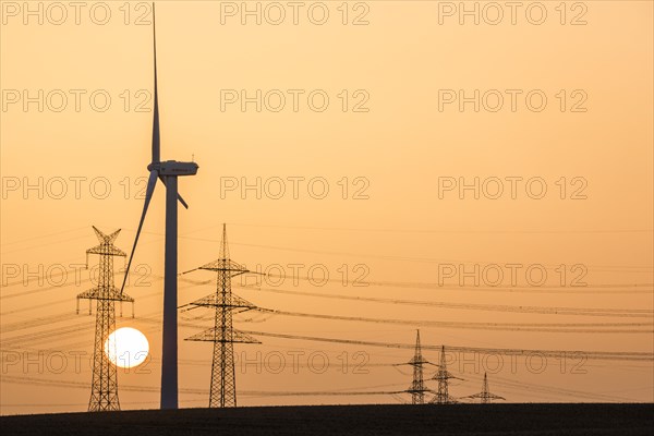 Wind turbine and power pole at sunset