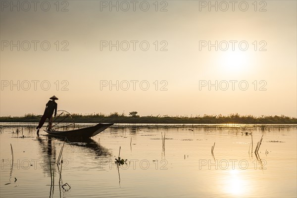Fisherman at Inle Lake with traditional Intha conical net at sunset