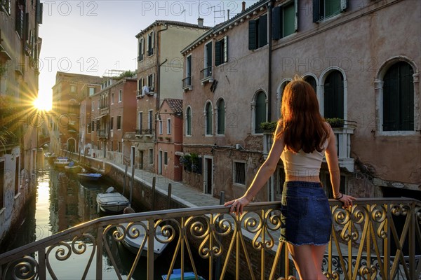 Young woman leaning against a bridge on the Rio Santa Catherina in the evening light