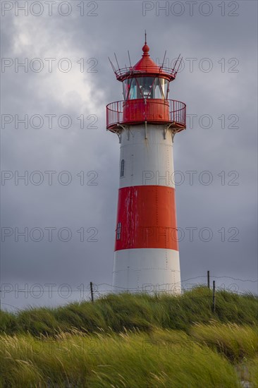 Red-white lighthouse List-Ost in the dunes in front of dark sky