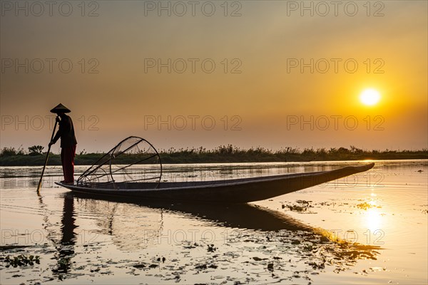 Fisherman at Inle Lake with traditional Intha conical net at sunset