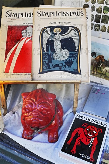 Shop window of an antiquarian bookshop with Simplicissimus books and red bulldog