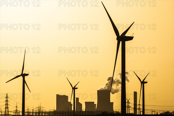 Wind turbines and power pylons at sunset in front of the lignite-fired power plant Niederaussem of RWE Power AG