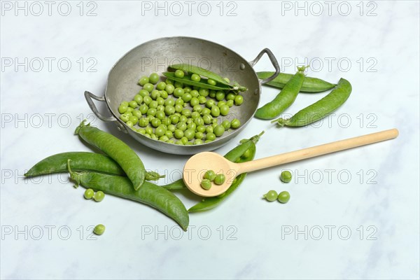 Green peas in pod and cooking spoon