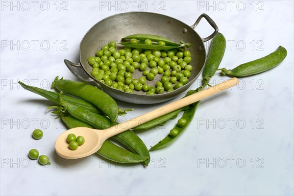 Green peas in pod and cooking spoon