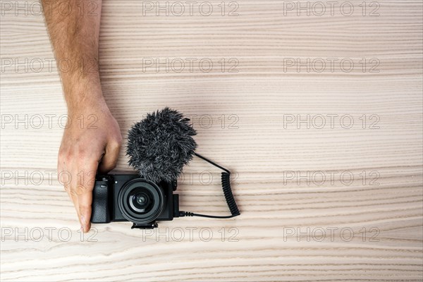 Hand holding little professional black camera with a microphone