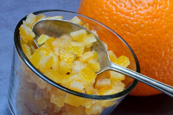 Candied orange peel cubes in glass with spoon