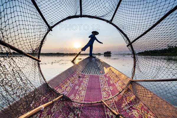 Fisherman at Inle Lake with traditional Intha conical net at sunset