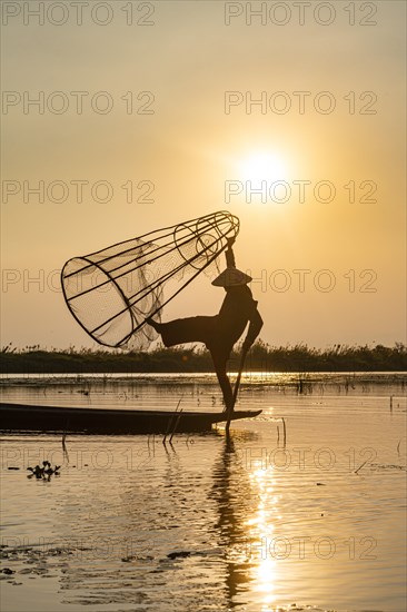 Fisherman at Inle Lake with traditional Intha conical net at sunset