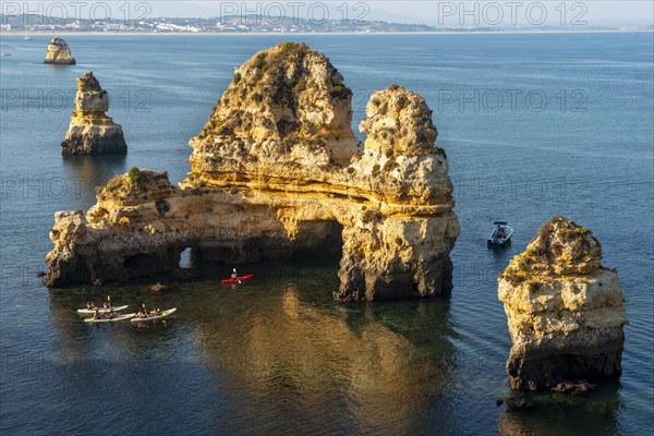 Kayakers paddling around rock formations in the sea