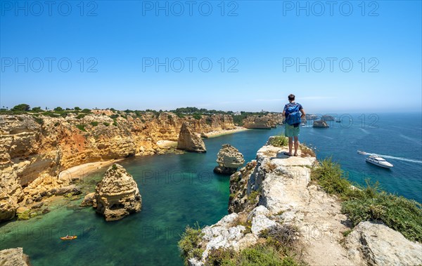 Young man standing on rocks on cliff