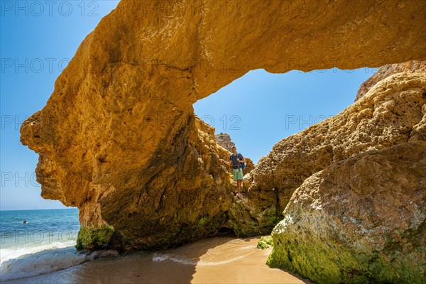 Young man standing in a rock cave with hole