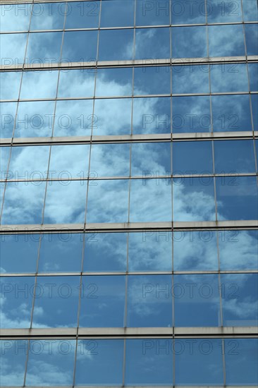 Glas facade with reflection of blue sky and clouds on a business building in Ginza district