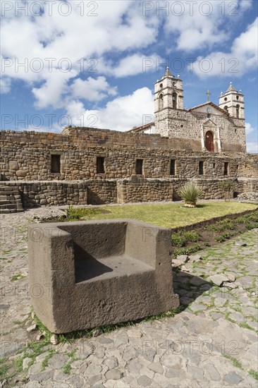 Stone throne in front of the Inca Sun Temple with attached cathedral from the colonial period