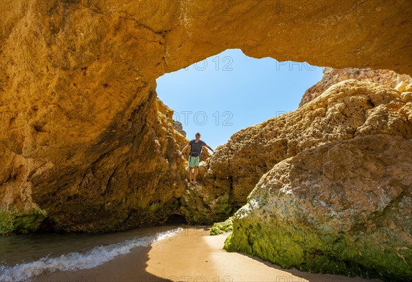 Young man standing in a rock cave with hole