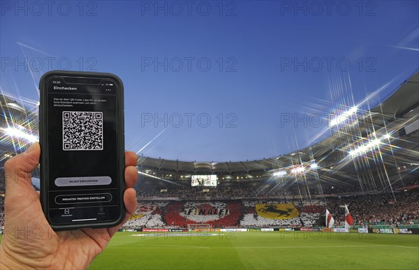 Hand holds smartphone with Luca app for digital contact tracking in packed football stadium