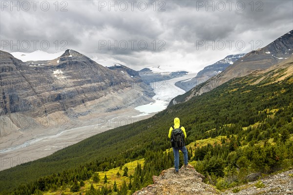 Hiker standing on rocks overlooking valley with glacier tongue