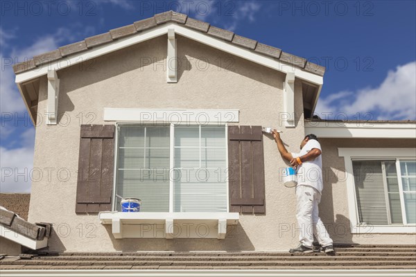 Busy house painter painting the trim and shutters of A home