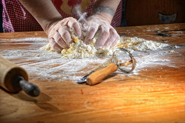 Cook kneading pasta dough on wooden table