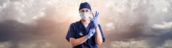 Doctor or nurse adjusting surgical gloves wearing personal protective equipment over ominous clouds