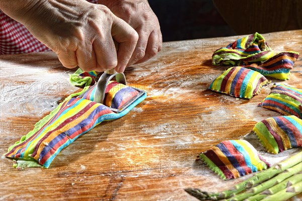 Cook cutting out fresh colorful ravioli with ravioli cutter