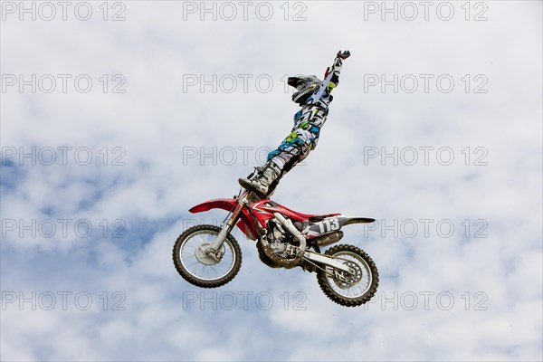 Motocross rider jumping in front of cloudy sky