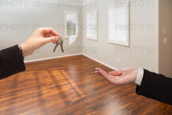 Real estate agent hands over new house keys inside empty room