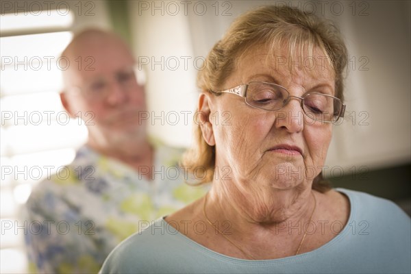 Senior adult couple in dispute or consoling in kitchen of house