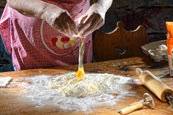 Cook making pasta dough on wooden table
