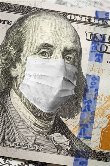 One hundred dollar bill with medical face mask on face of benjamin franklin