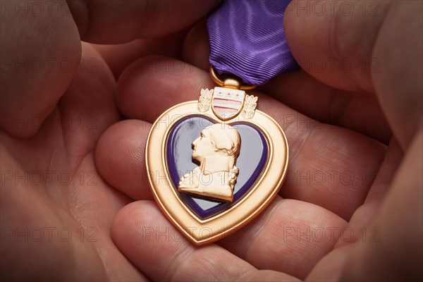 Male hand holding the United States armed forces purple heart medal