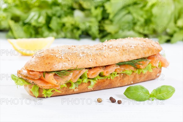 Roll sandwich wholemeal baguette topped with salmon fish on wooden board