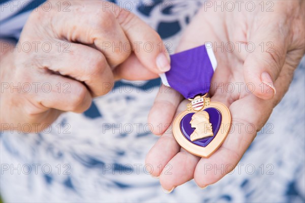 Senior woman holding the United States military purple heart medal in her hands