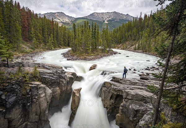 Young man standing at Sunwapta Falls waterfall